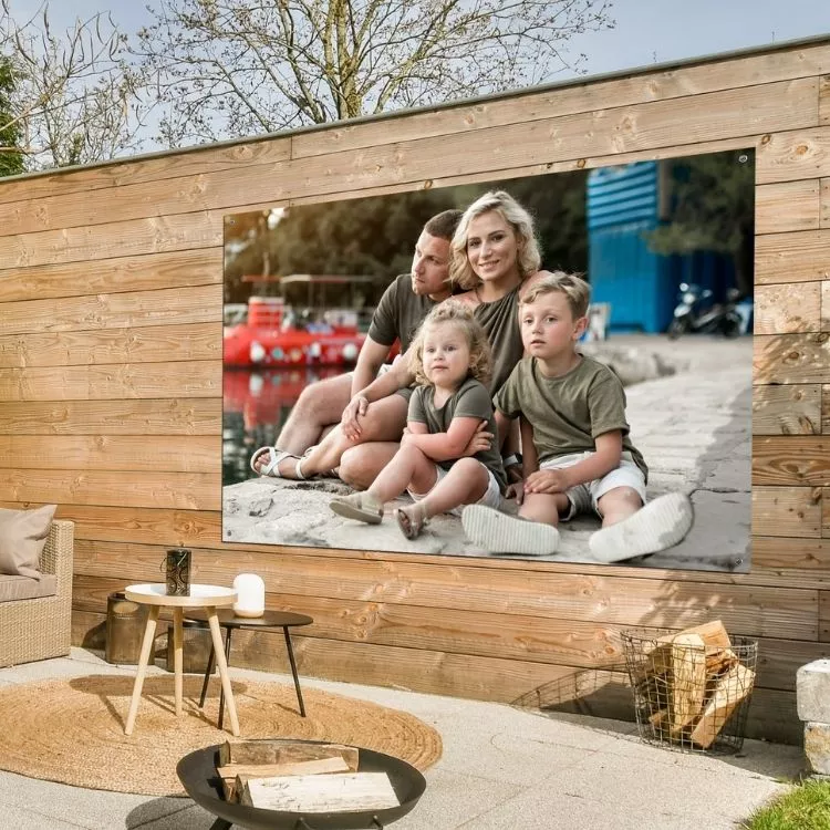 Een foto op tuinposter van een gezin hangt aan de schutting.