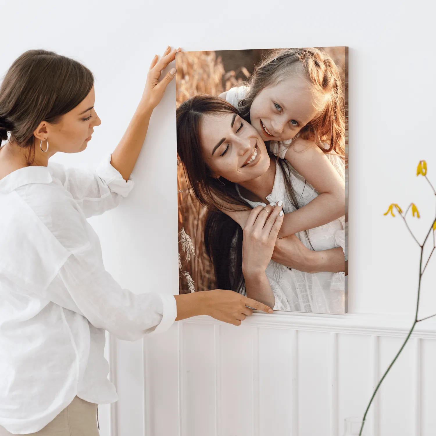 Een vrouw is een persoonlijk schilderij aan het ophangen