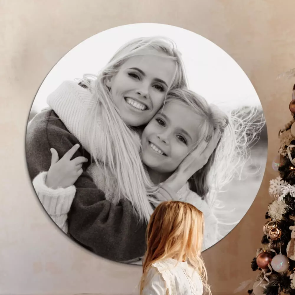 Een zwart-wit wandcirkel van een moeder met dochter hangt aan de muur naast een kerstboom