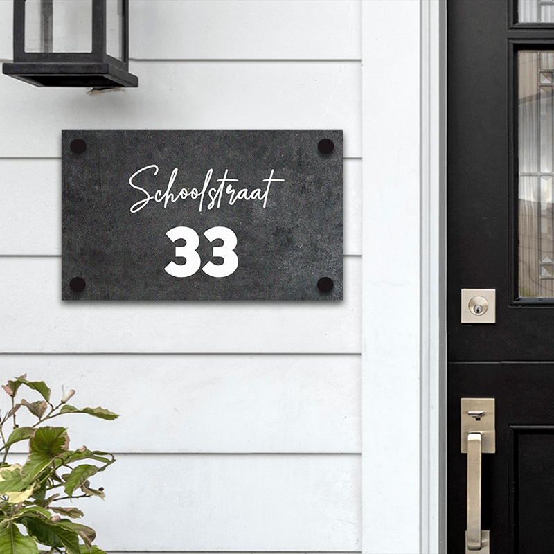 Een naambordje met de tekst 'Schoolstraat 33' hangt aan de muur