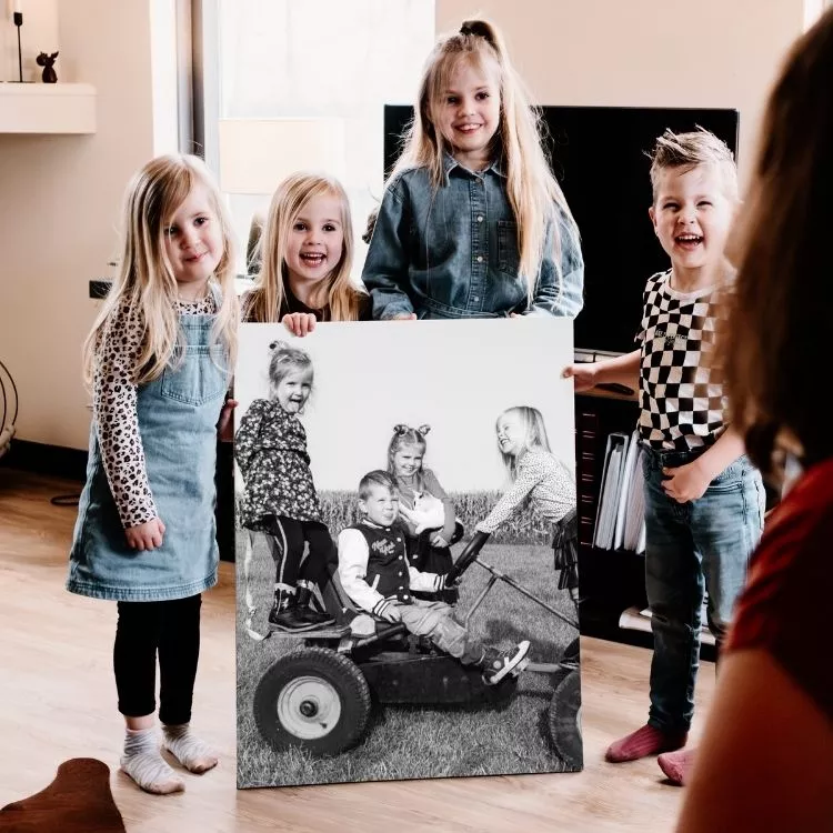 Vier kinderen houden een foto op canvas vast. 